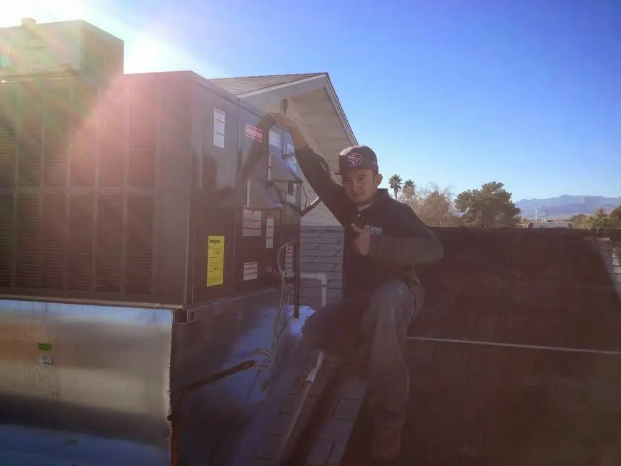 HVAC technician performing Air Duct Repair on a rooftop unit in Sabattus